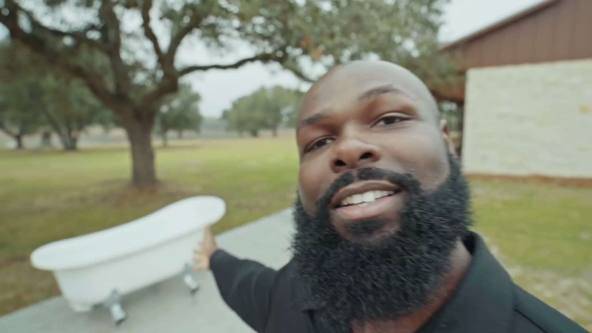 Justin Porter pointing at a white clawfoot bathtub set up on a lawn