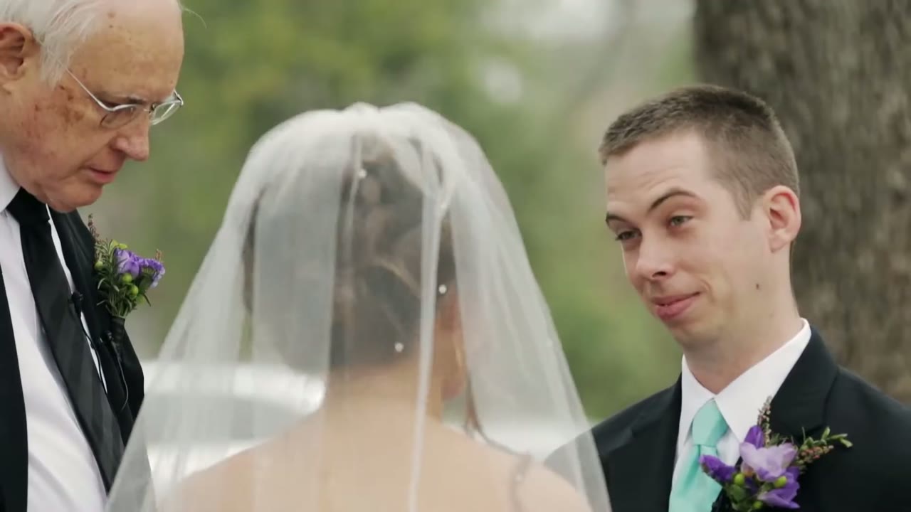 Groom smiling at the bride through her veil as the officiant reads beside them