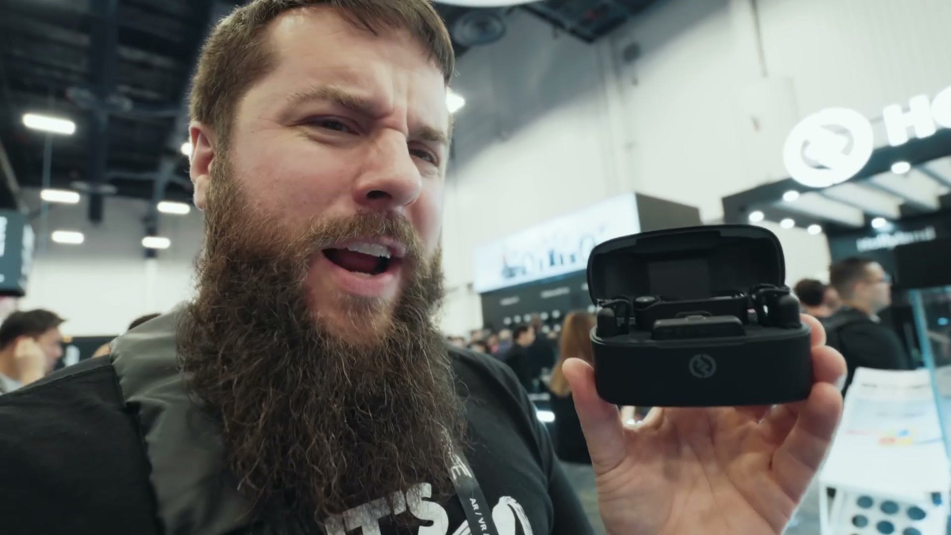 Matt holding the open charging case of the Hollyland Lark Max 2 wireless microphone system in front of the Hollyland booth