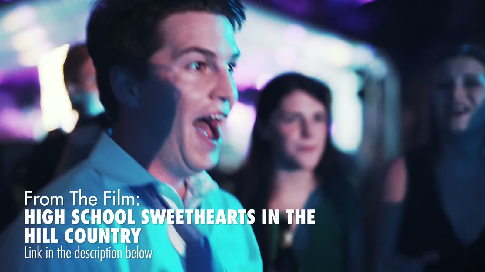 Young man singing joyfully under colorful lights with friends behind him, captioned 'High School Sweethearts In The Hill Country'