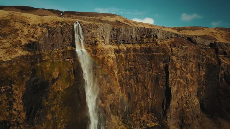 A waterfall dropping over the edge of a high cliff into a canyon, with no people anywhere in frame