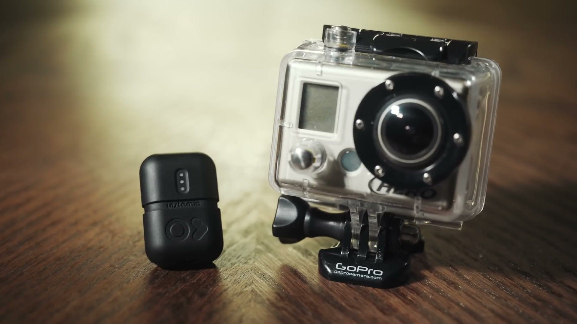 The black Instamic Pro standing on a wooden table next to an original GoPro in its housing