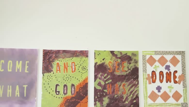 Four hand-painted canvases hung in a row on a white wall, spelling out Come And See What God Has Done