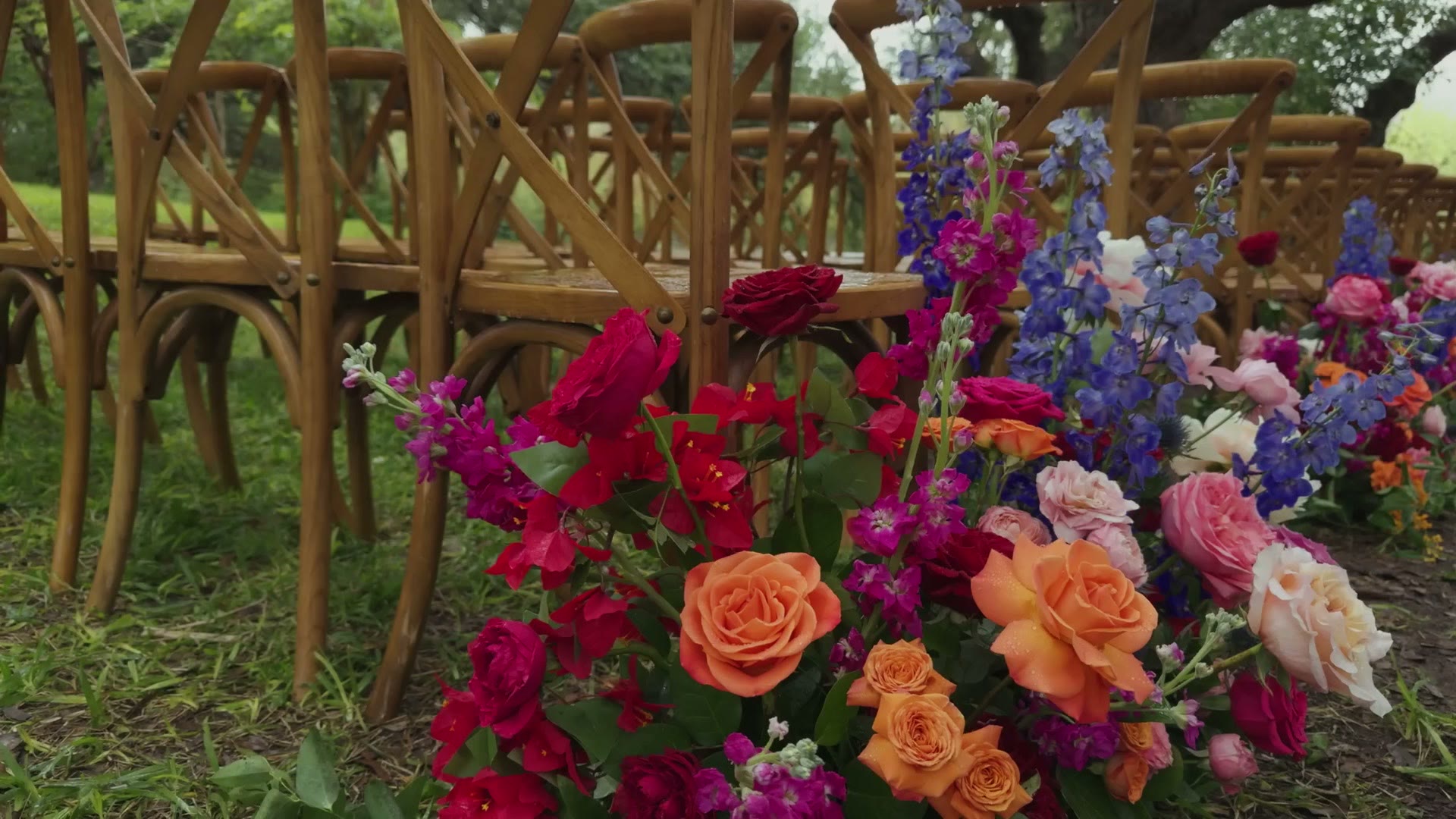 Close up iPhone footage of colourful wedding florals beside ceremony chairs