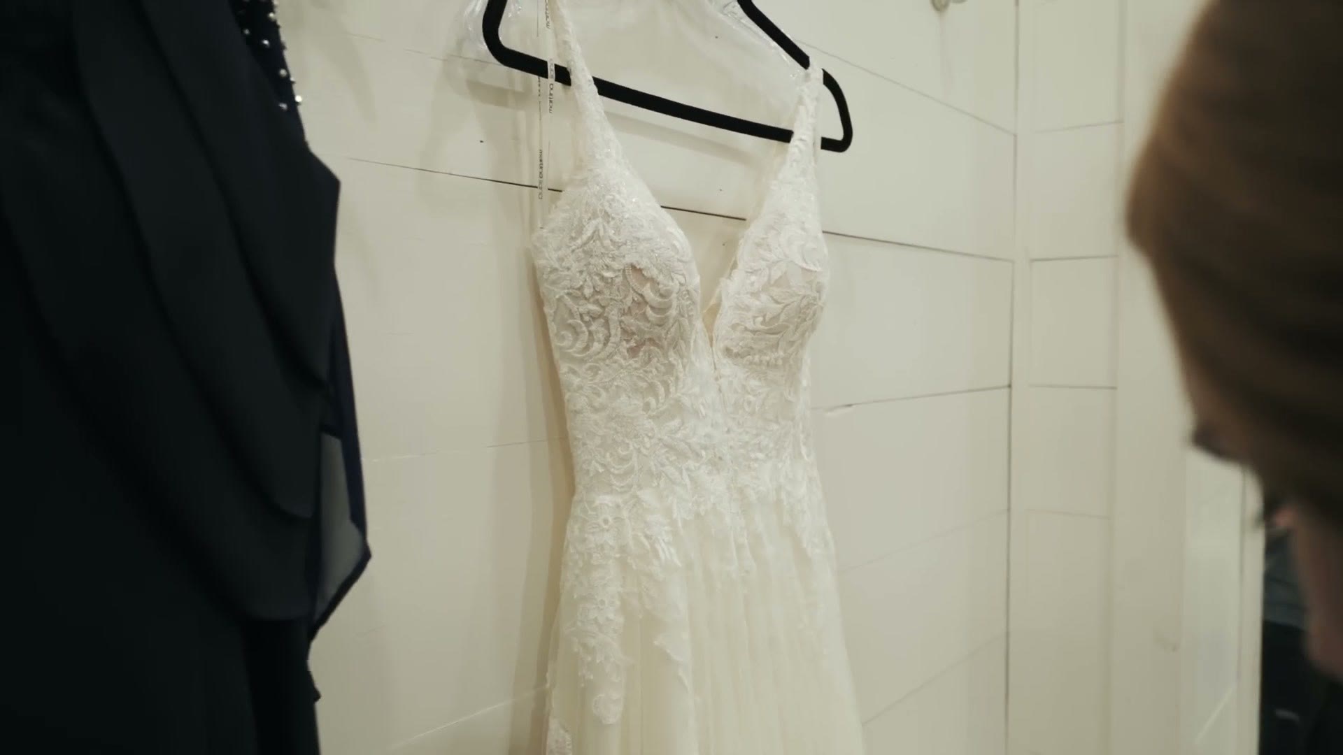 The finished wedding dress hanging on a hanger with the lav mic and cord no longer visible anywhere on it.