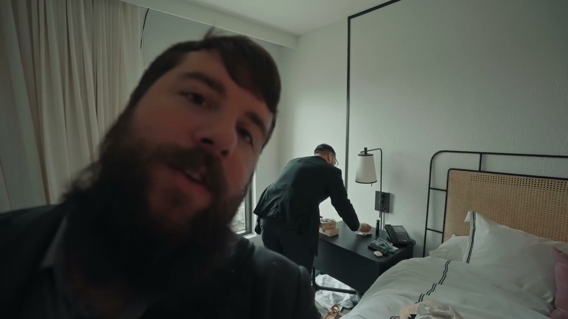 Groom getting ready in a hotel room while being filmed