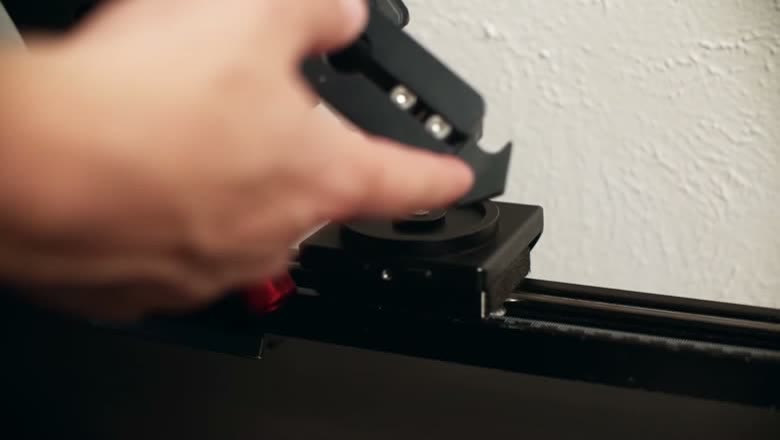 A hand attaching the Master Pan's panning mount to the carriage of a Konova slider