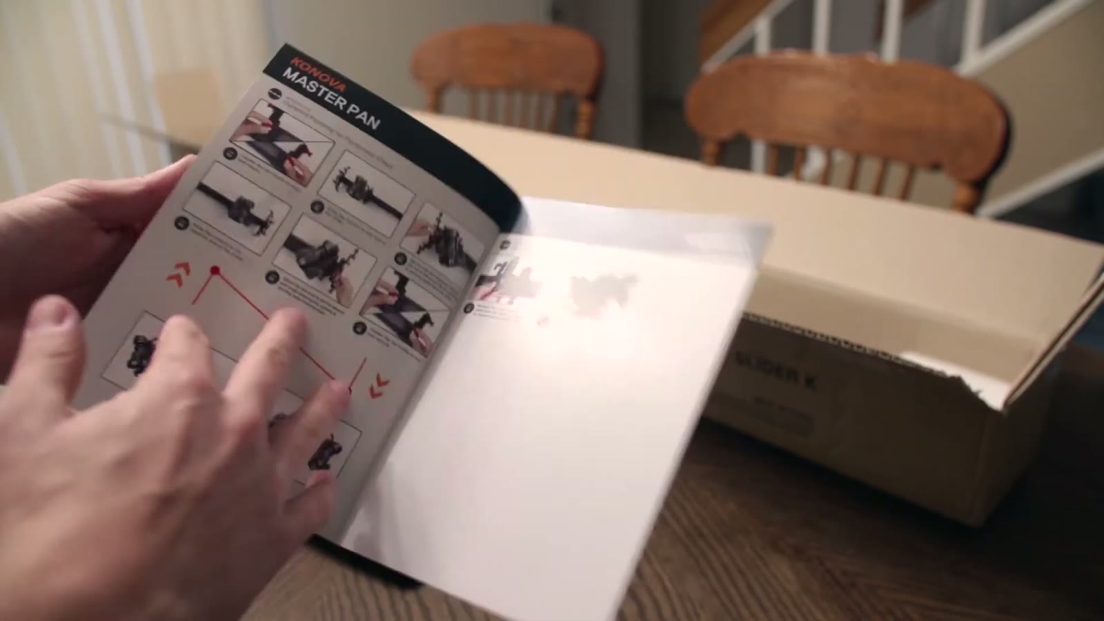 Hands flipping open the Konova Master Pan manual showing step-by-step assembly diagrams