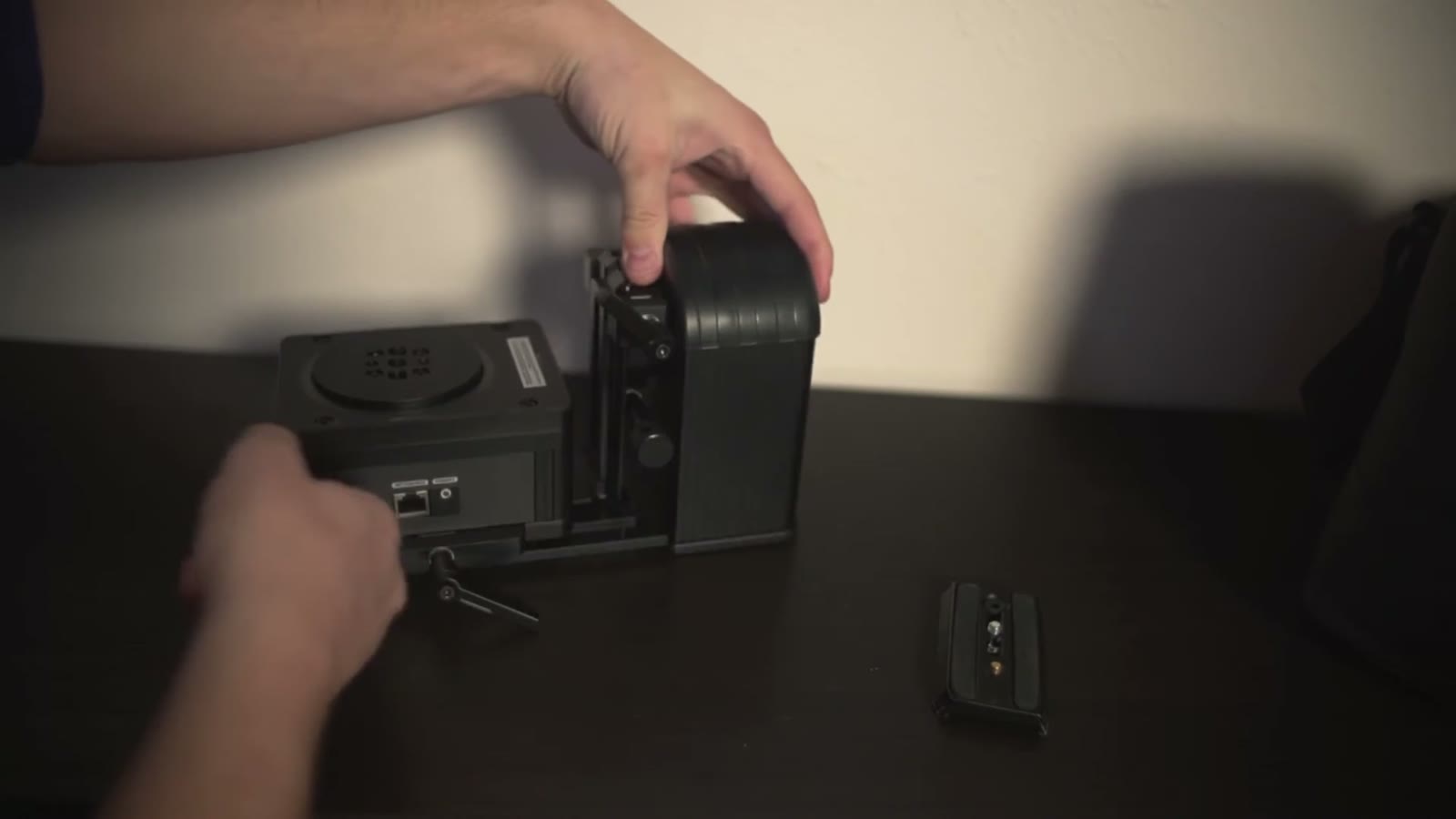 Hands attaching the Smart Head motor unit onto its slider mounting plate on a dark tabletop