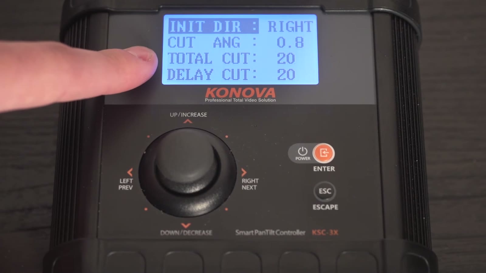 Konova controller screen with INIT DIR: RIGHT highlighted, CUT ANG: 0.8, TOTAL CUT: 20, DELAY CUT: 20, finger on the dial