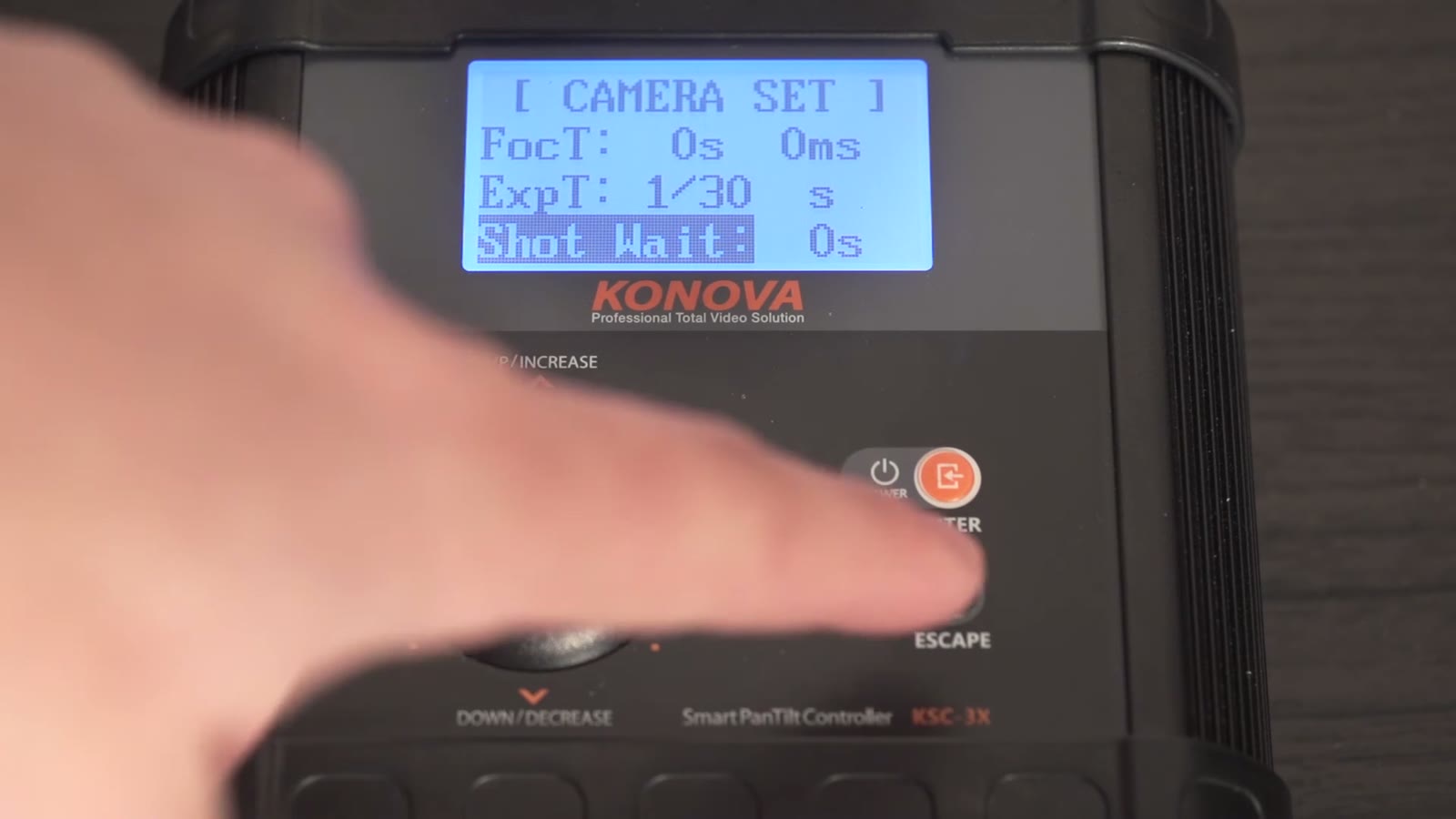 Konova Camera Set menu showing FocT: 0s 0ms, ExpT: 1/30s, Shot Wait: 0s highlighted, finger near the Enter button