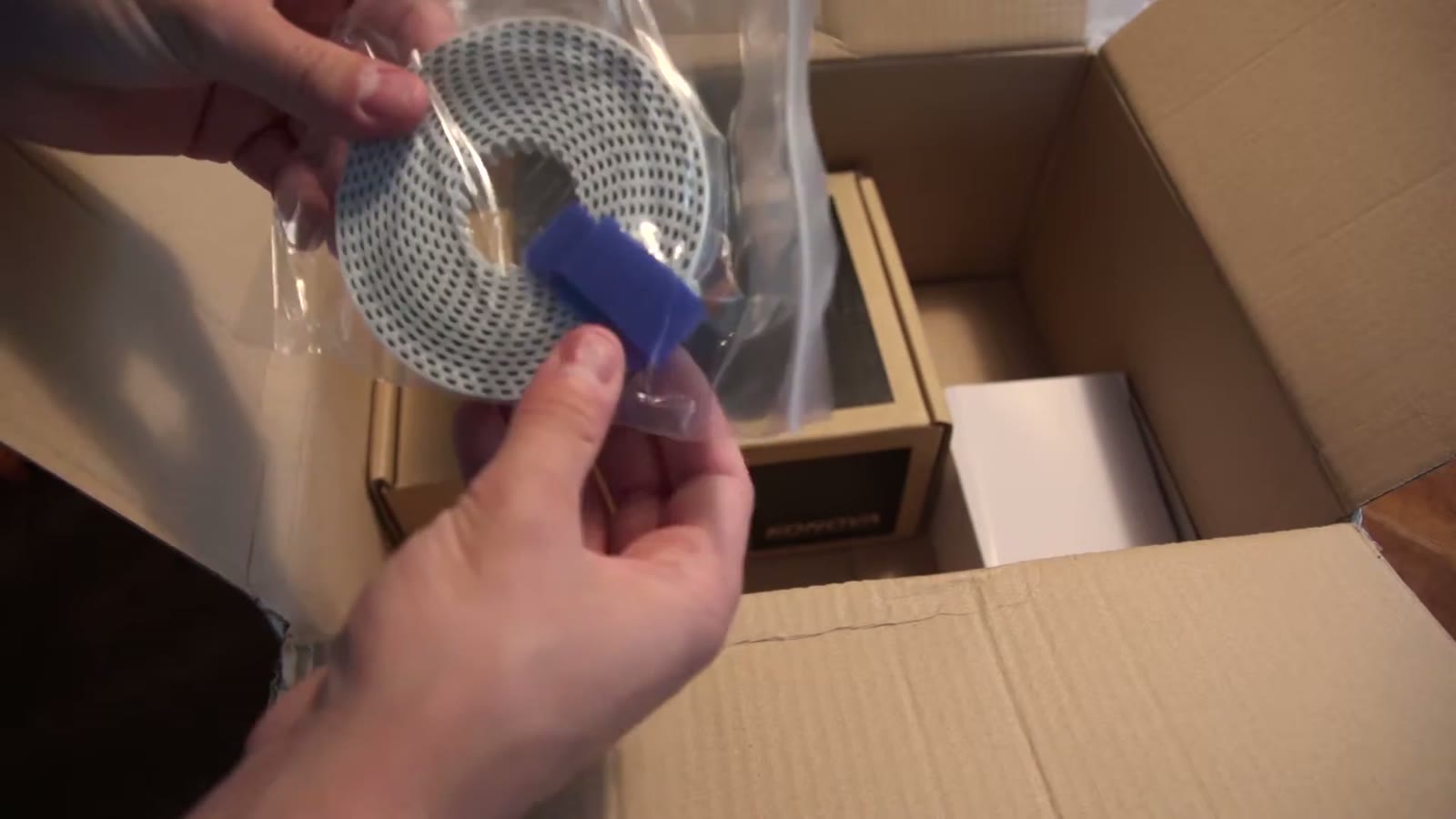 Coiled gray timing belt held up out of its plastic bag