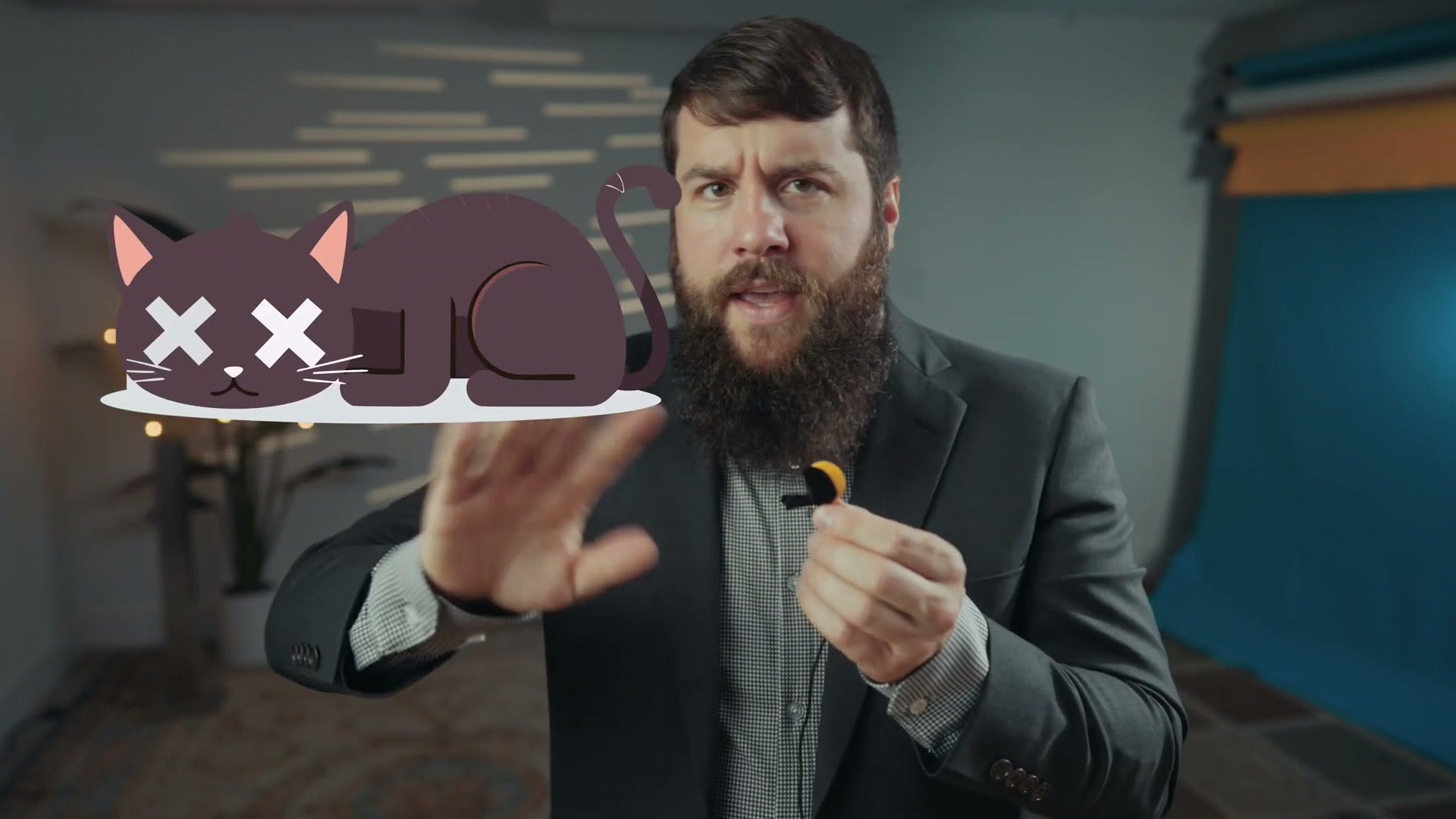 Matt holding a fuzzy windscreen for a lavalier microphone with a cartoon dead cat graphic on screen