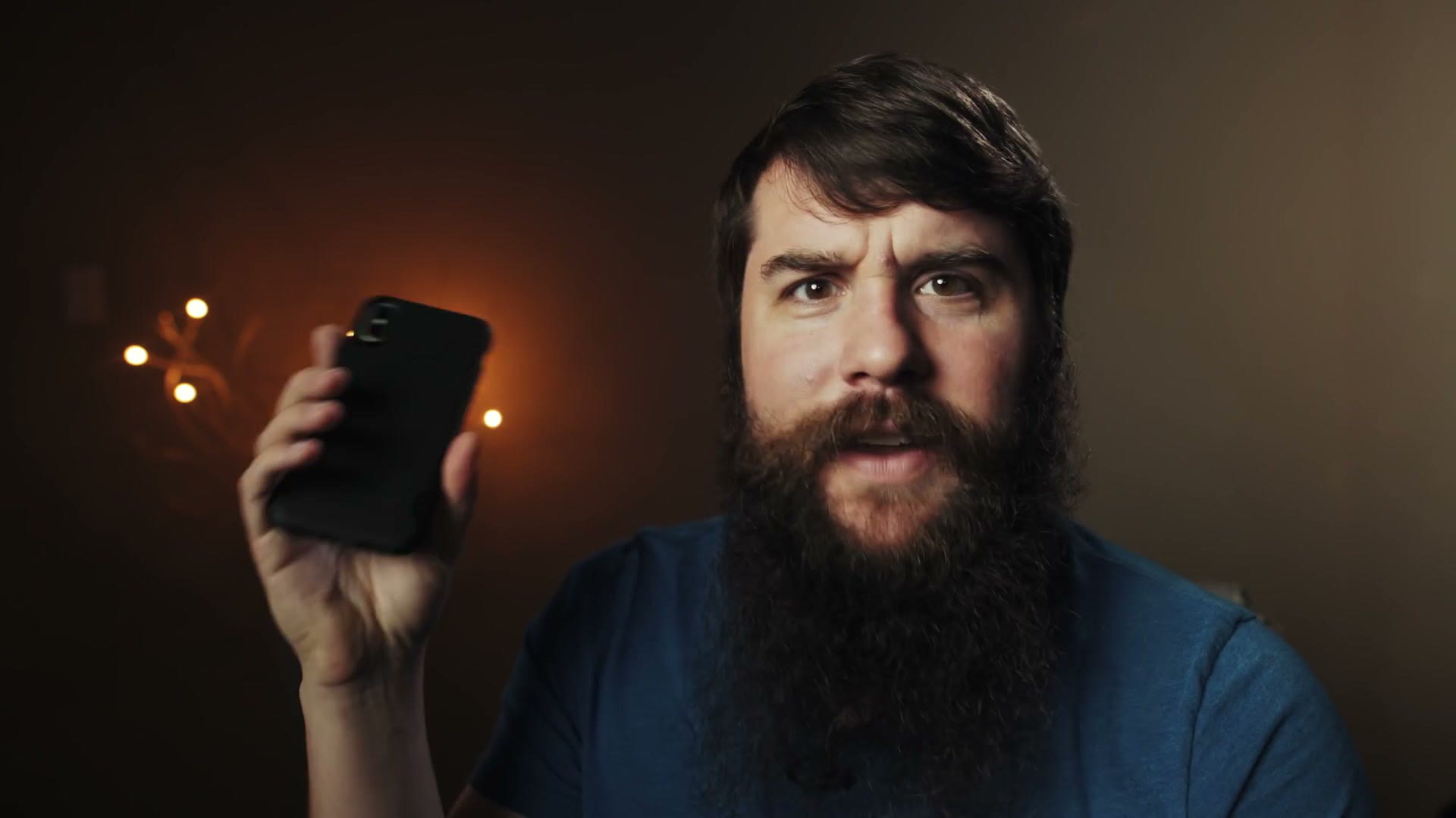 Matt holding up a smartphone with its camera facing away from him.