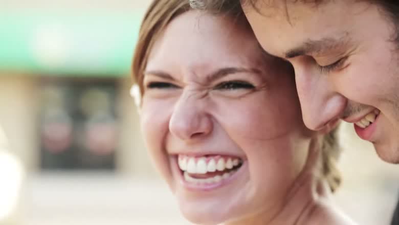 The bride laughing with her whole face while the groom leans in beside her, both mid-laugh