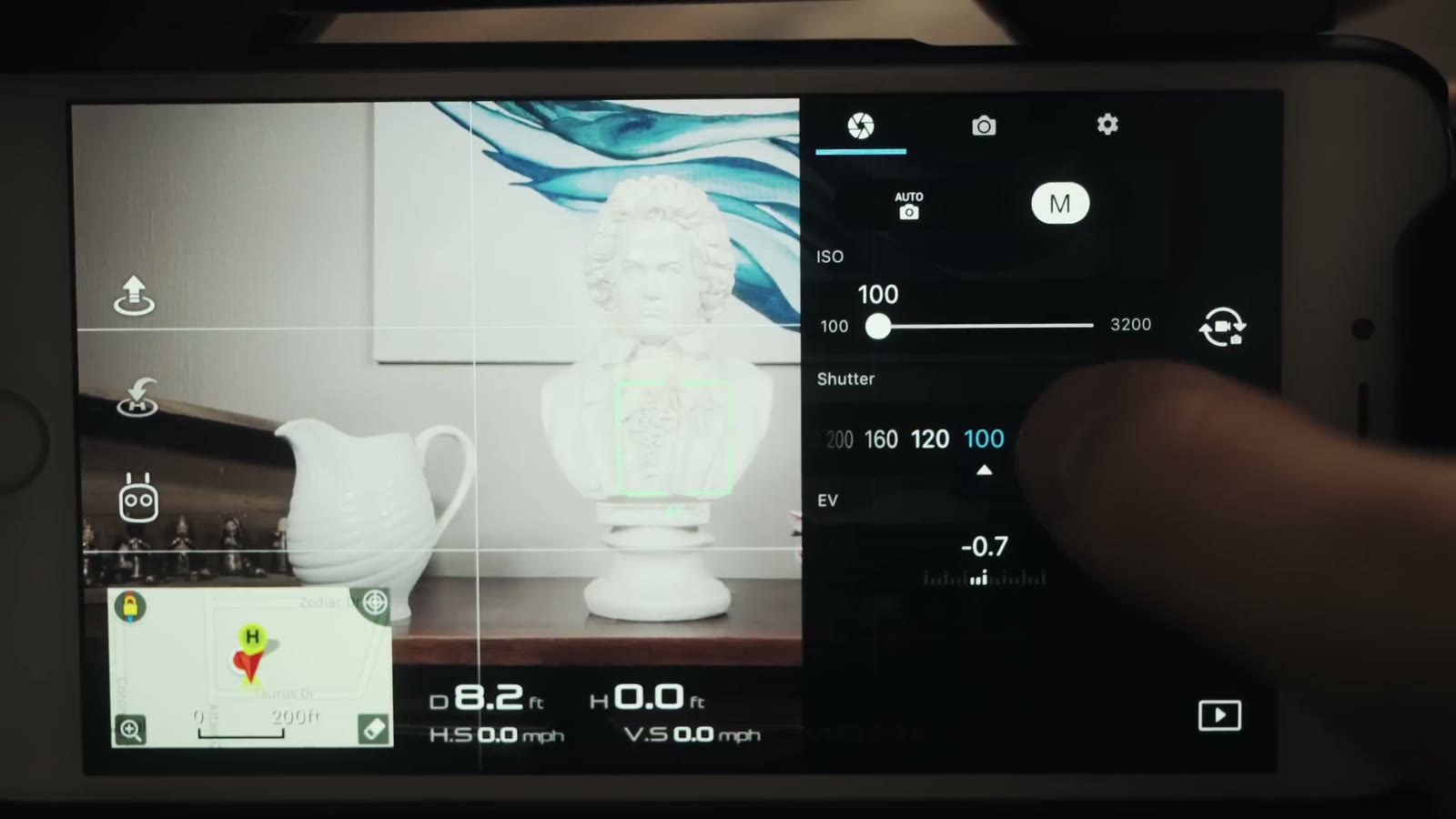 The DJI Go manual exposure panel showing ISO 100 and a shutter row with 200, 160, 120 and 100, and EV at minus 0.7