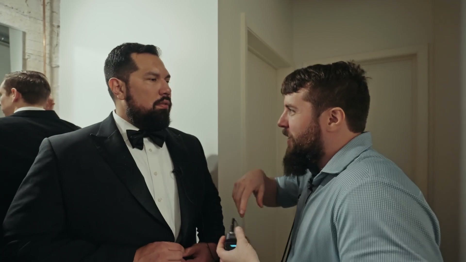 Matt attaching a microphone to a groom in a tuxedo before the ceremony
