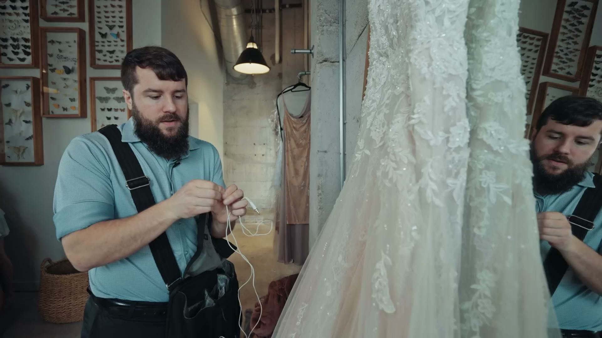 Matt attaching a small white lavalier microphone to a wedding dress on a hanger