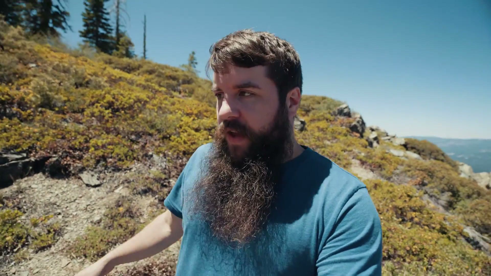 Matt Johnson on a mountain ridge with wildflowers scouting a portrait location