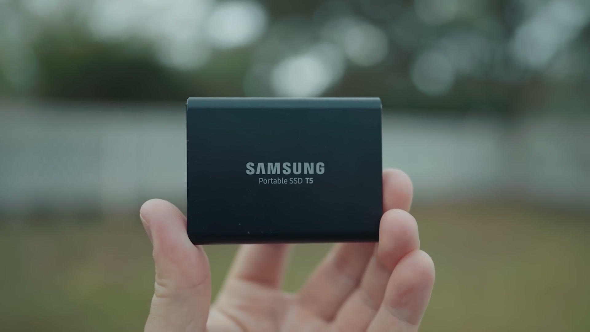 A Samsung portable SSD held in one hand outdoors