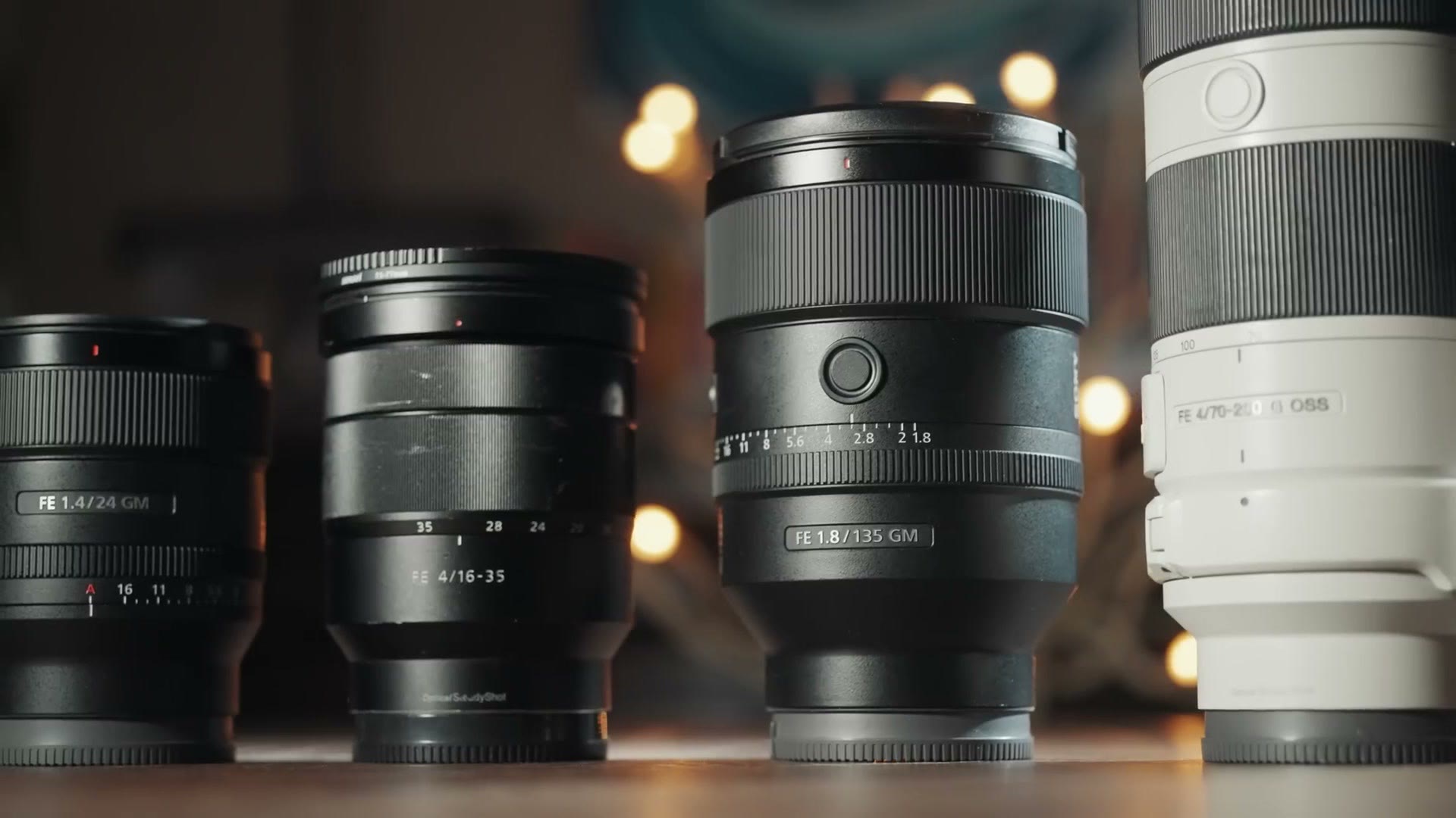Four Sony lenses lined up, a 24mm GM, a 16-35, a 135mm GM and a white 70-200