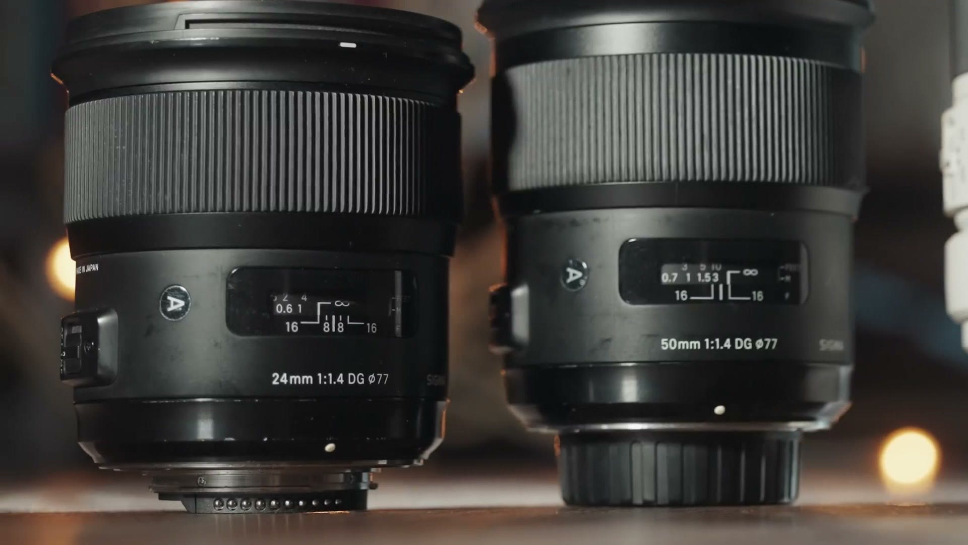 Two Sigma prime lenses side by side, a 24mm 1.4 and a 50mm 1.4, both marked with a 77mm filter thread