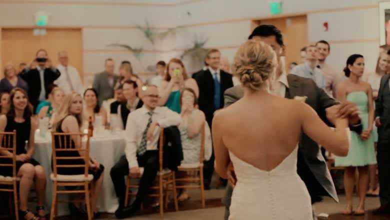 The bride being led back down the aisle as a room full of seated and standing guests applaud and photograph