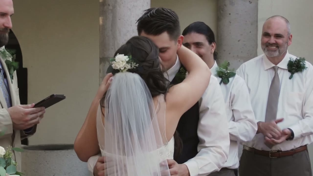 Bride hugging the groom at the altar, officiant reading and groomsmen smiling behind them