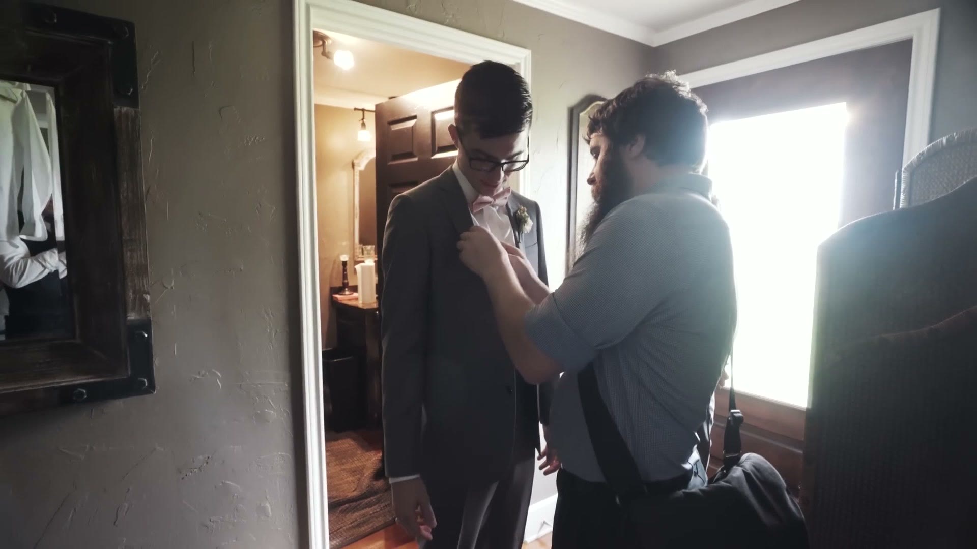 Matt attaching a lavalier microphone to the groom's suit jacket in the getting ready room