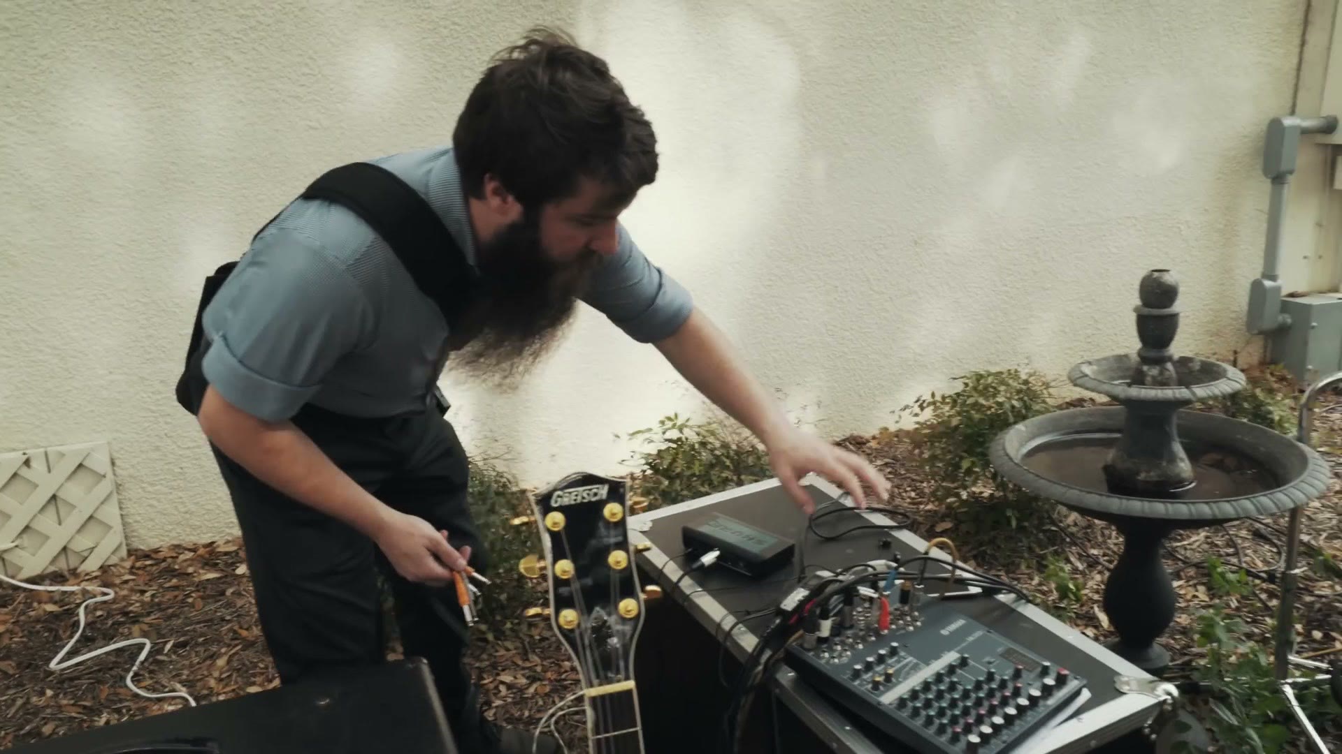 Matt crouched beside the venue's small mixing board and amplifier outside, plugging a cable into it