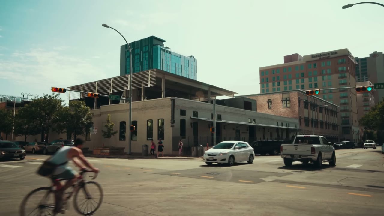 A downtown Austin street corner with traffic, a cyclist and office buildings