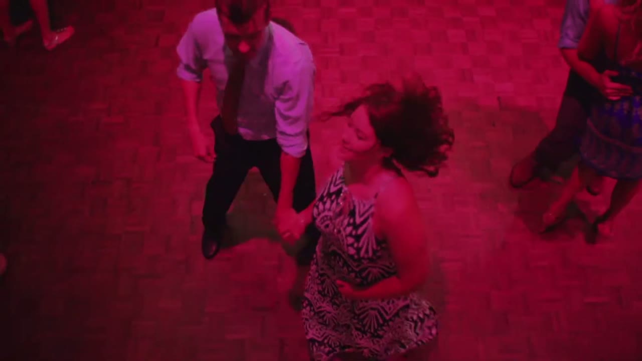 Overhead shot of a couple dancing on a wooden floor lit entirely in red at the reception