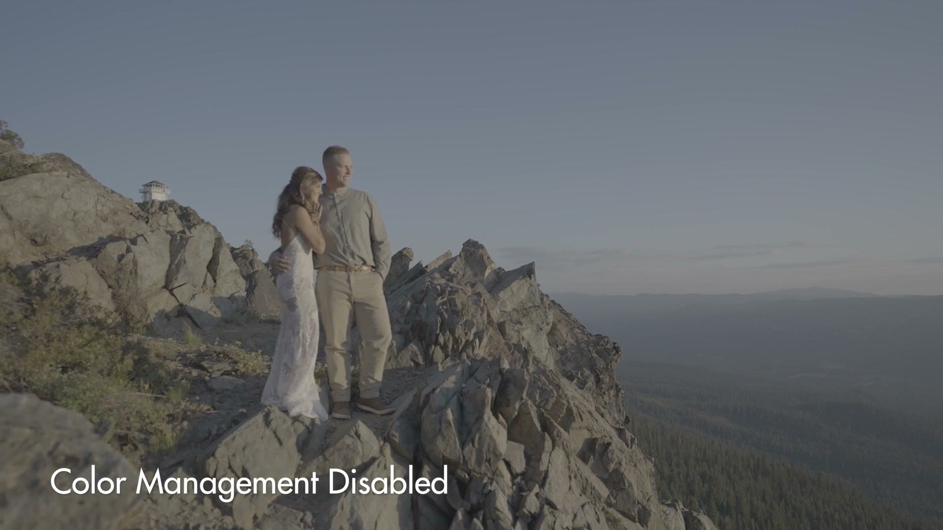 A flat, grey, desaturated S-Log3 shot of a couple standing on a mountain ridge, labeled Color Management Disabled