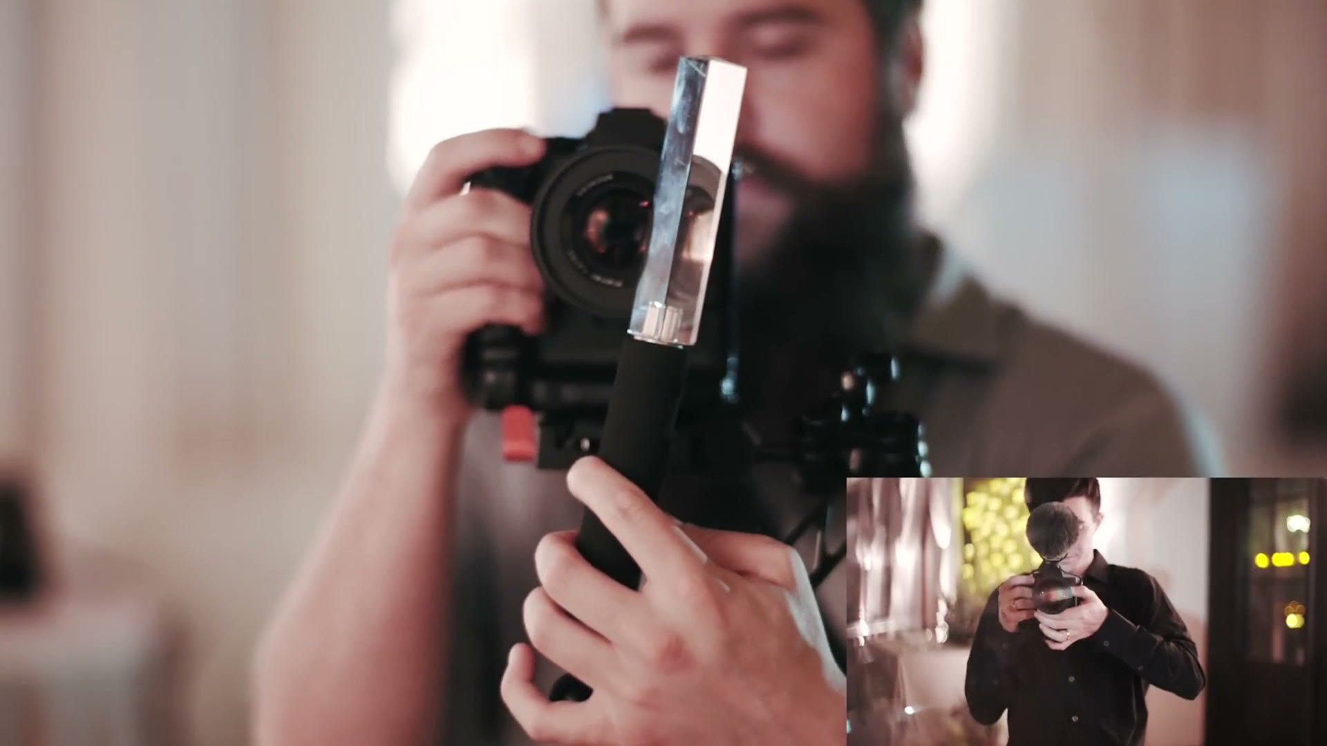 A camera held in both hands with a triangular prism mounted on an articulating arm in front of the lens
