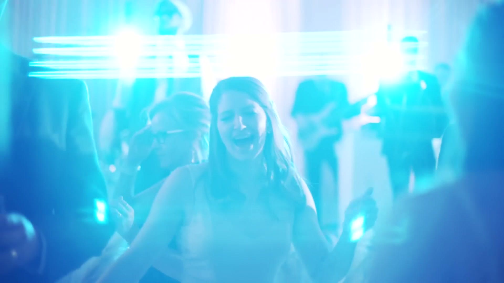 A wedding reception dance floor under blue light with long horizontal light streaks running across the frame from the chromatic flare filter