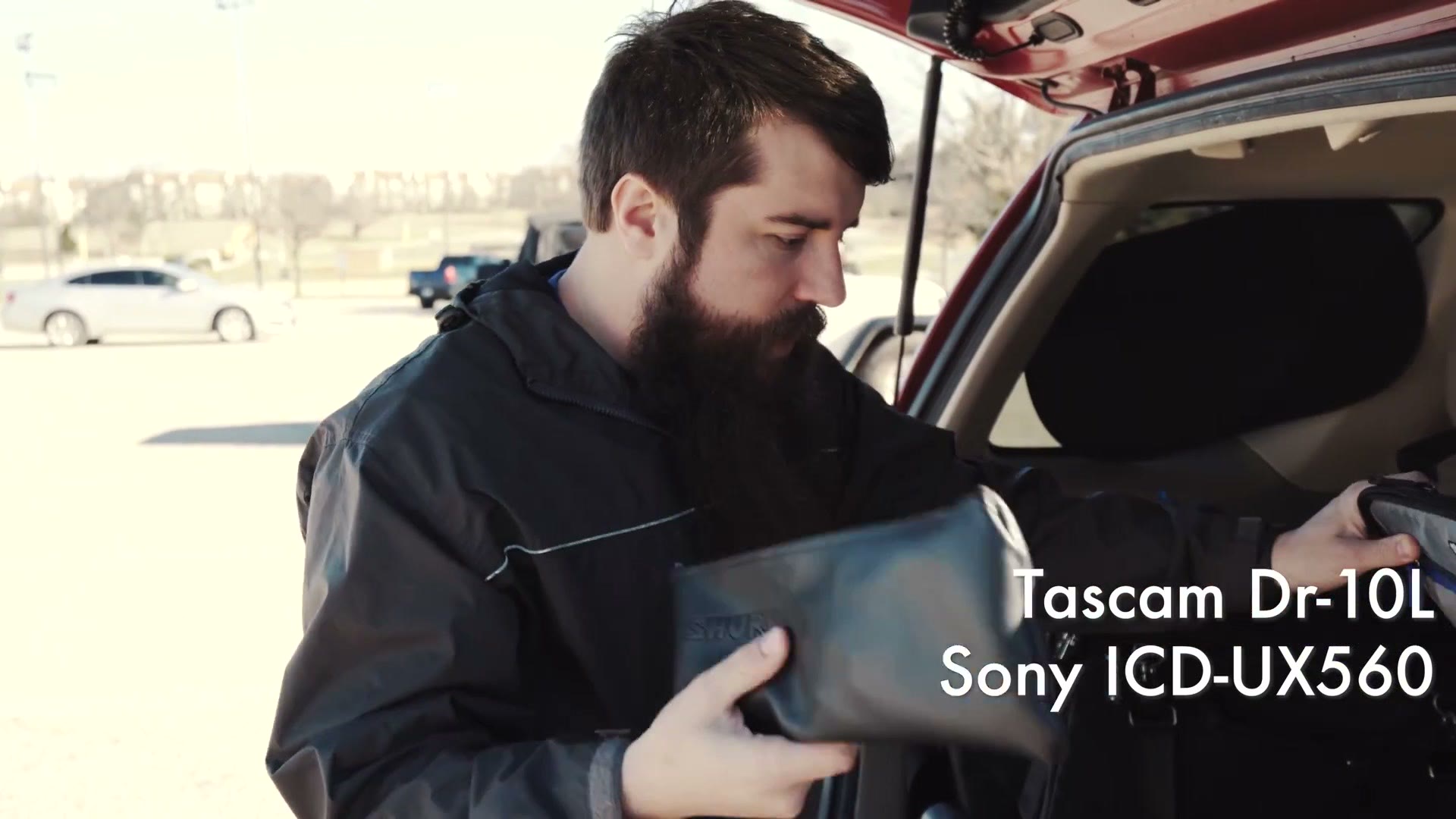 Matt holding a small pouch of audio gear beside his car, with on-screen text reading Tascam Dr-10L and Sony ICD-UX560.