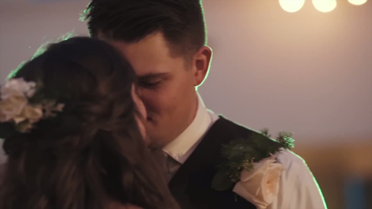 Close-up of the bride and groom kissing during their first dance, white flowers in her hair