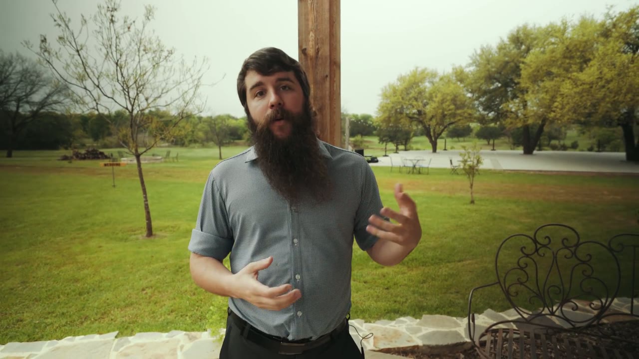 Matt talking to camera on a covered porch overlooking an open grassy venue property