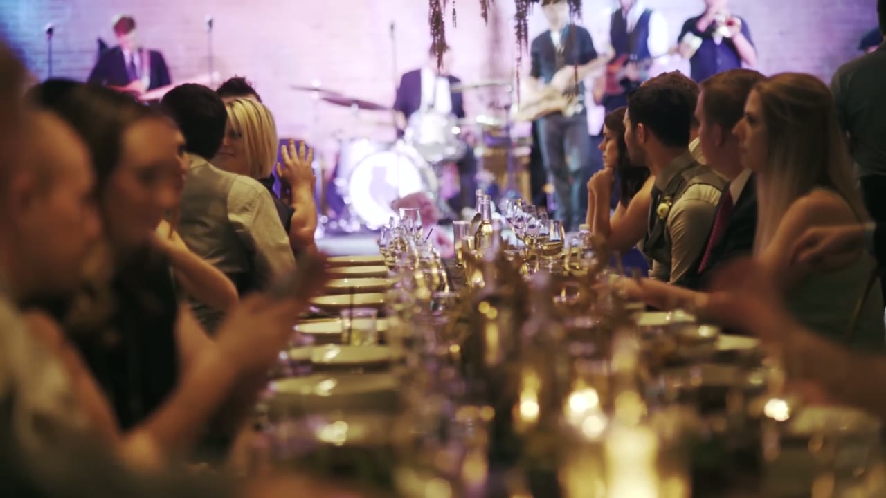 Reception tables lined with candles and glassware while the live band plays behind