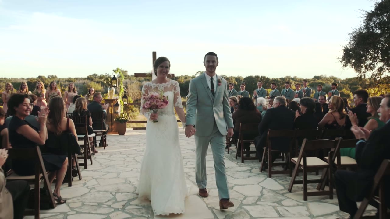 Bride and groom walking hand in hand back down the aisle, guests clapping on both sides