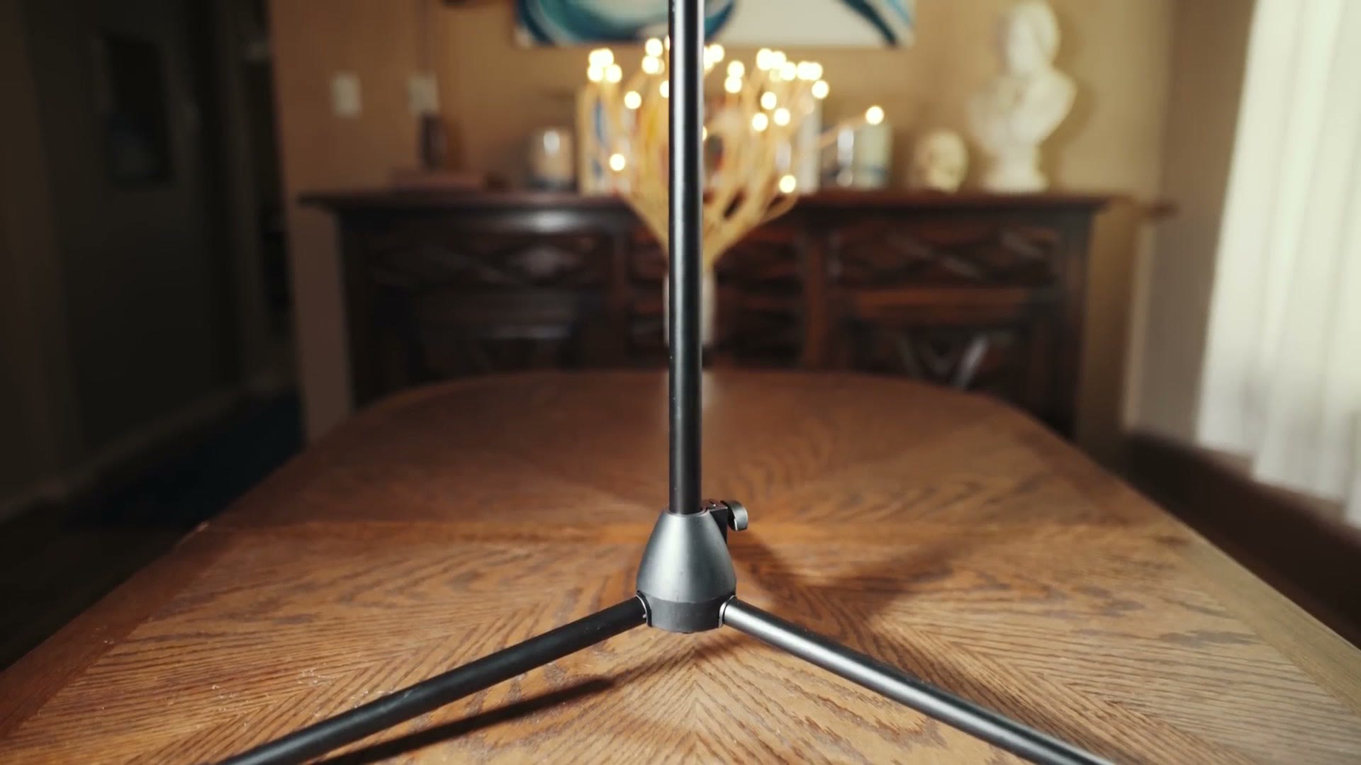 A folding tripod microphone stand set up on a dining table