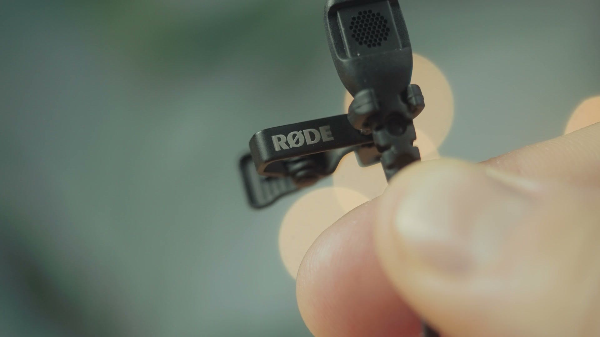 A large fuzzy windscreen for the Rode lav microphone held in one hand
