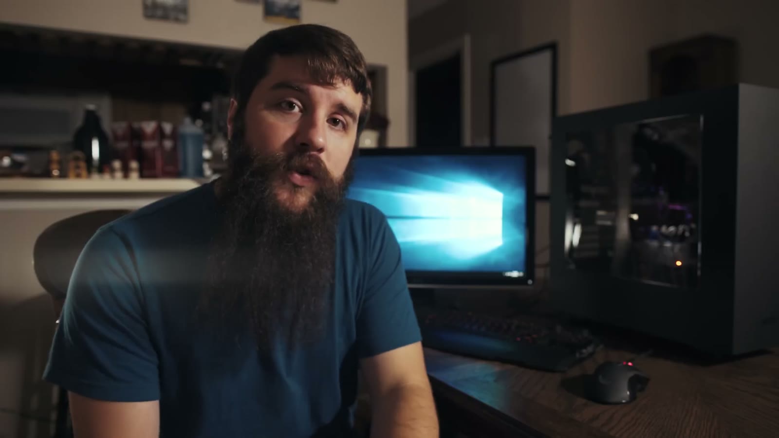 Matt talking to camera at night with the blue-lit PC and a Windows 10 lock screen monitor behind him