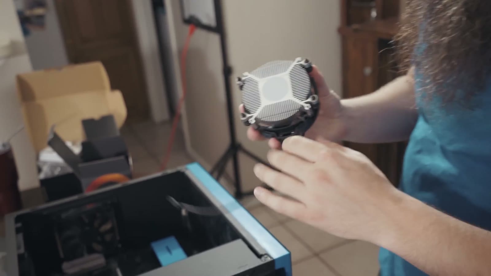 Close-up of hands holding a CPU cooler fan unit next to the open case
