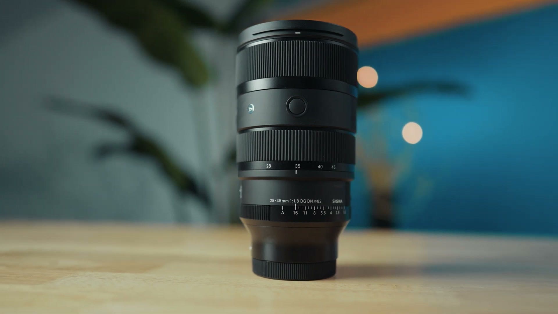 Sigma 28-45mm f1.8 lens standing on a wooden desk