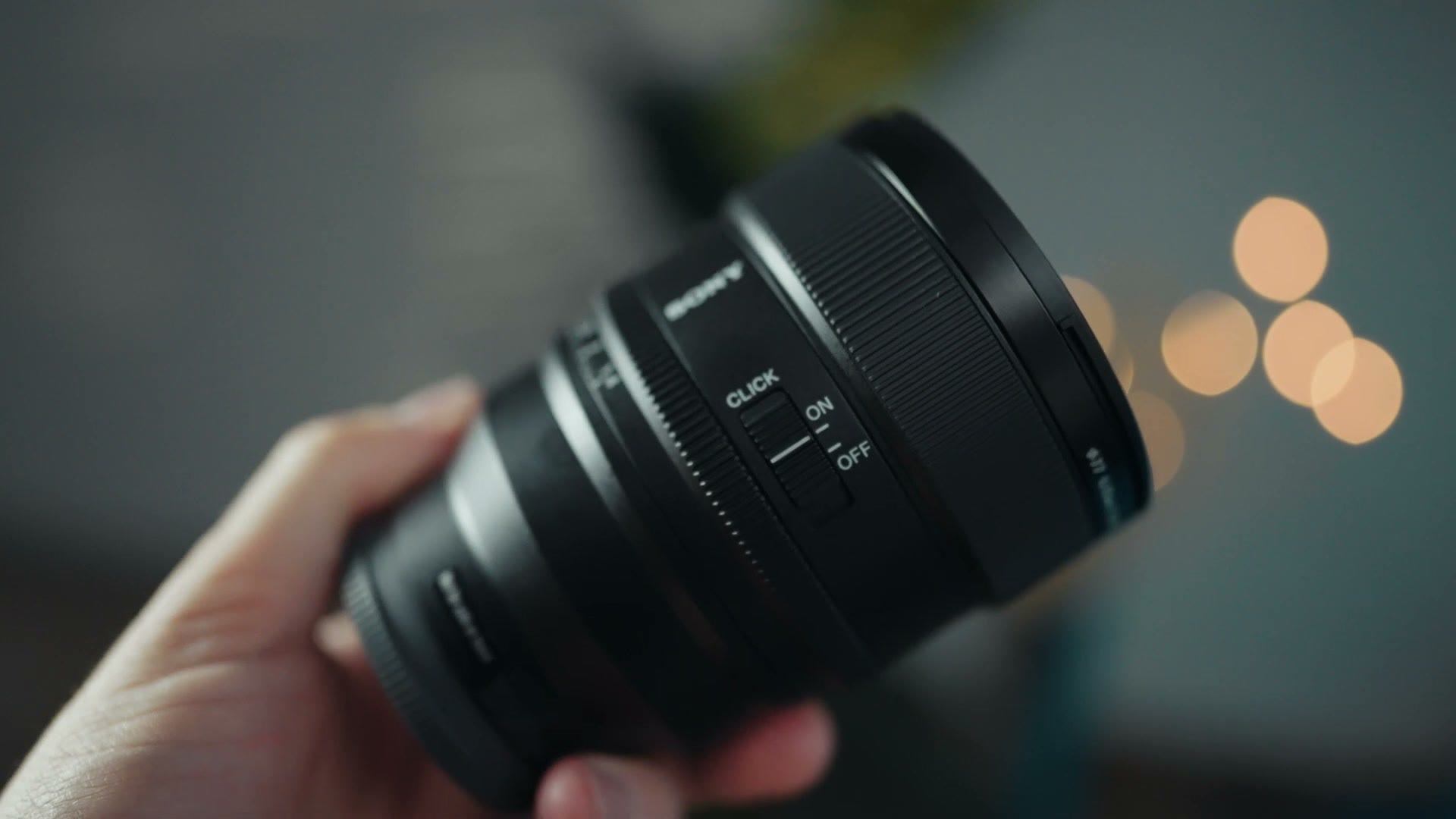 Sony 85mm GM II held in hand showing the click on off switch
