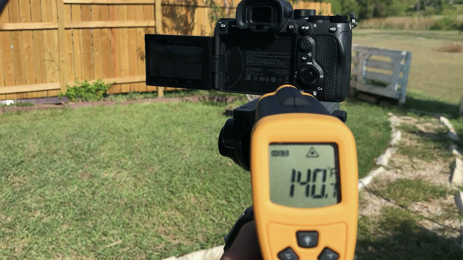 Infrared thermometer reading 140.7 degrees pointed at a Sony camera outdoors