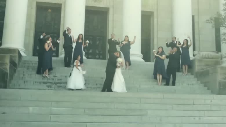 The couple coming down the wide front steps of the church between two rows of the bridal party throwing petals into the air