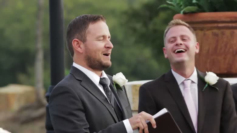 The officiant and the groom both laughing hard during the ceremony, the officiant still holding his book