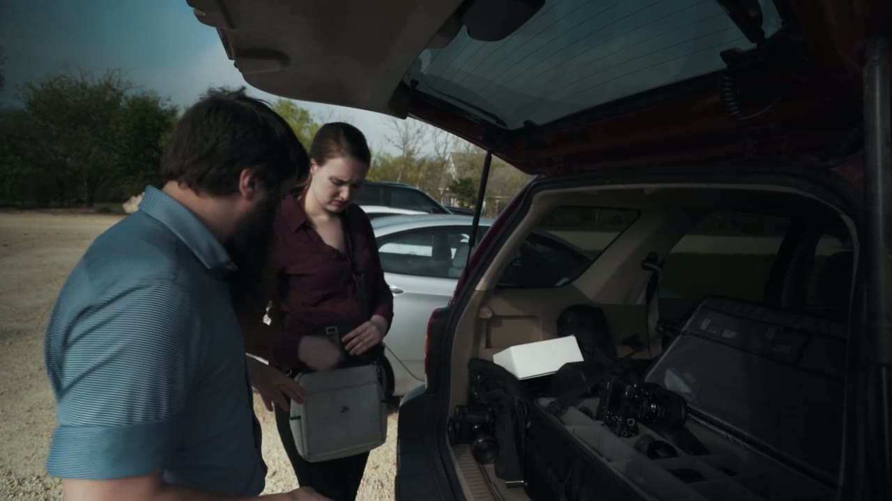 Matt and Rachel sorting camera cases and a second lens box out of the packed trunk